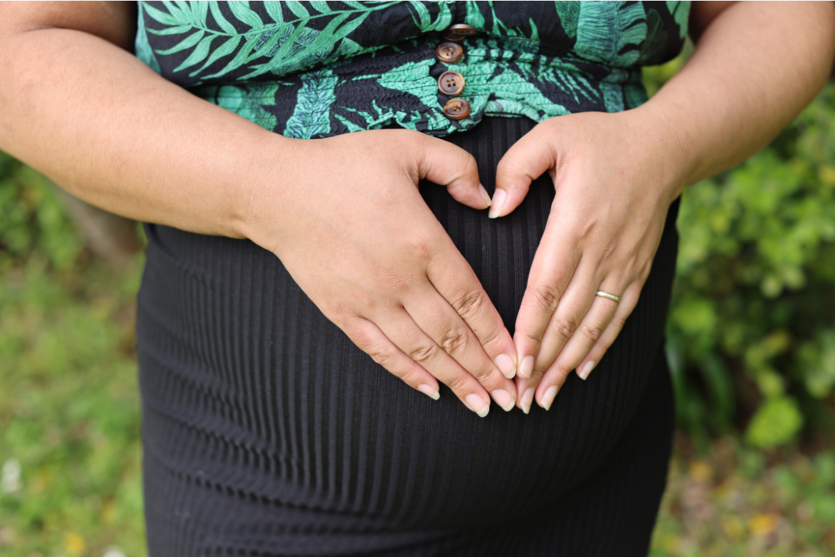 Pregnant pacific mums hands on stomach in tropical garden 