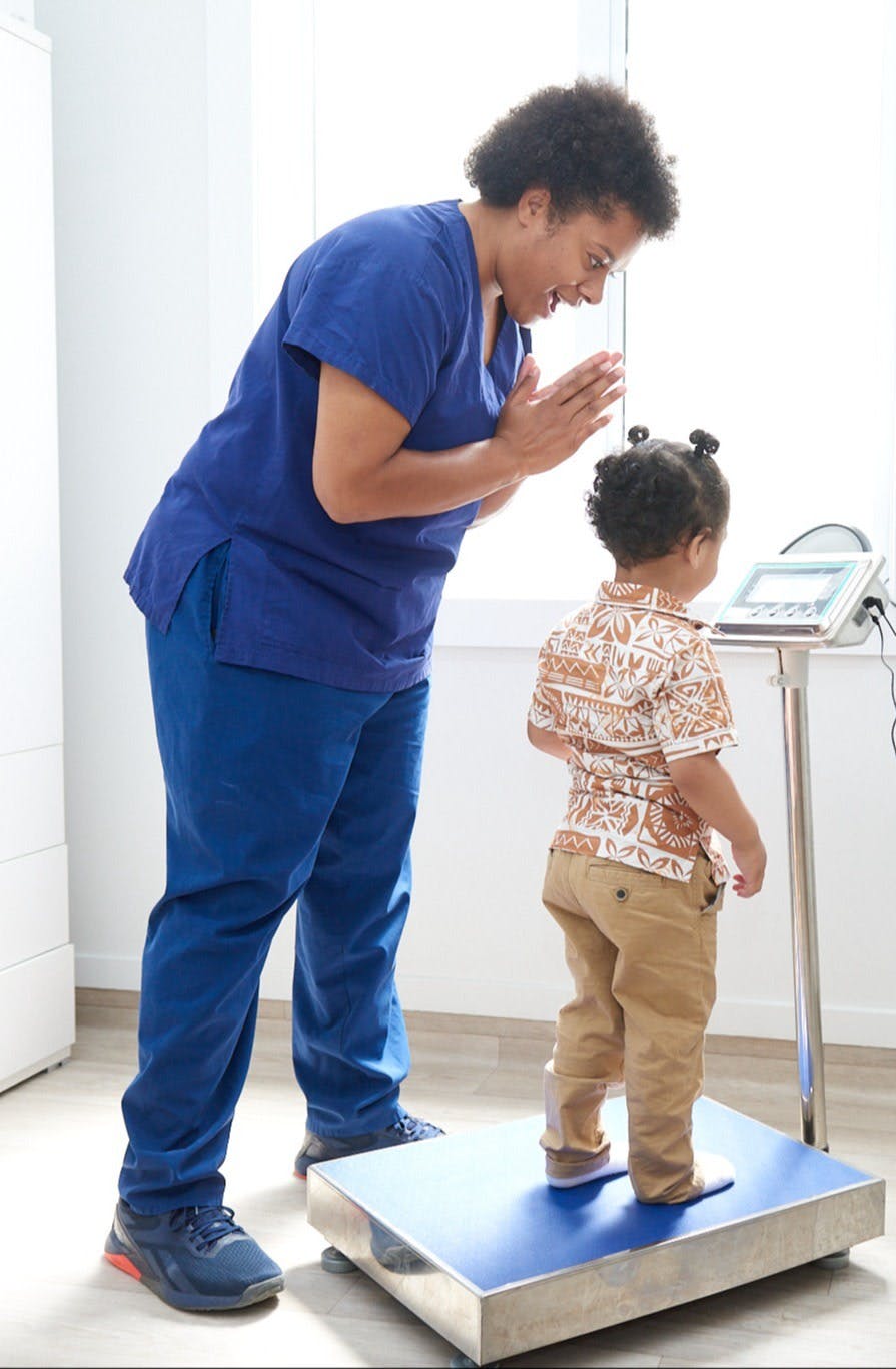 nurse standing with child on scale