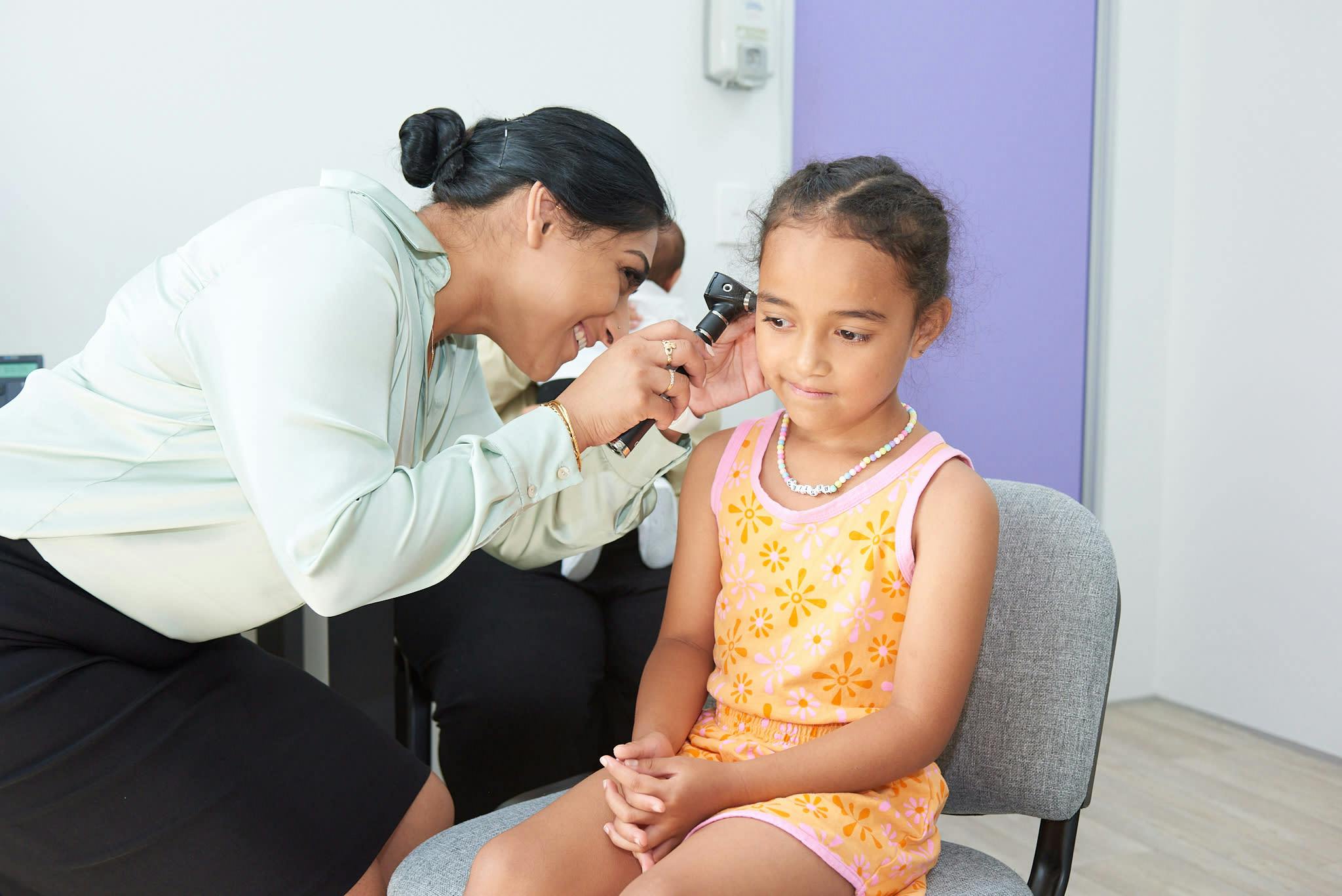 female doctor checking female child ear