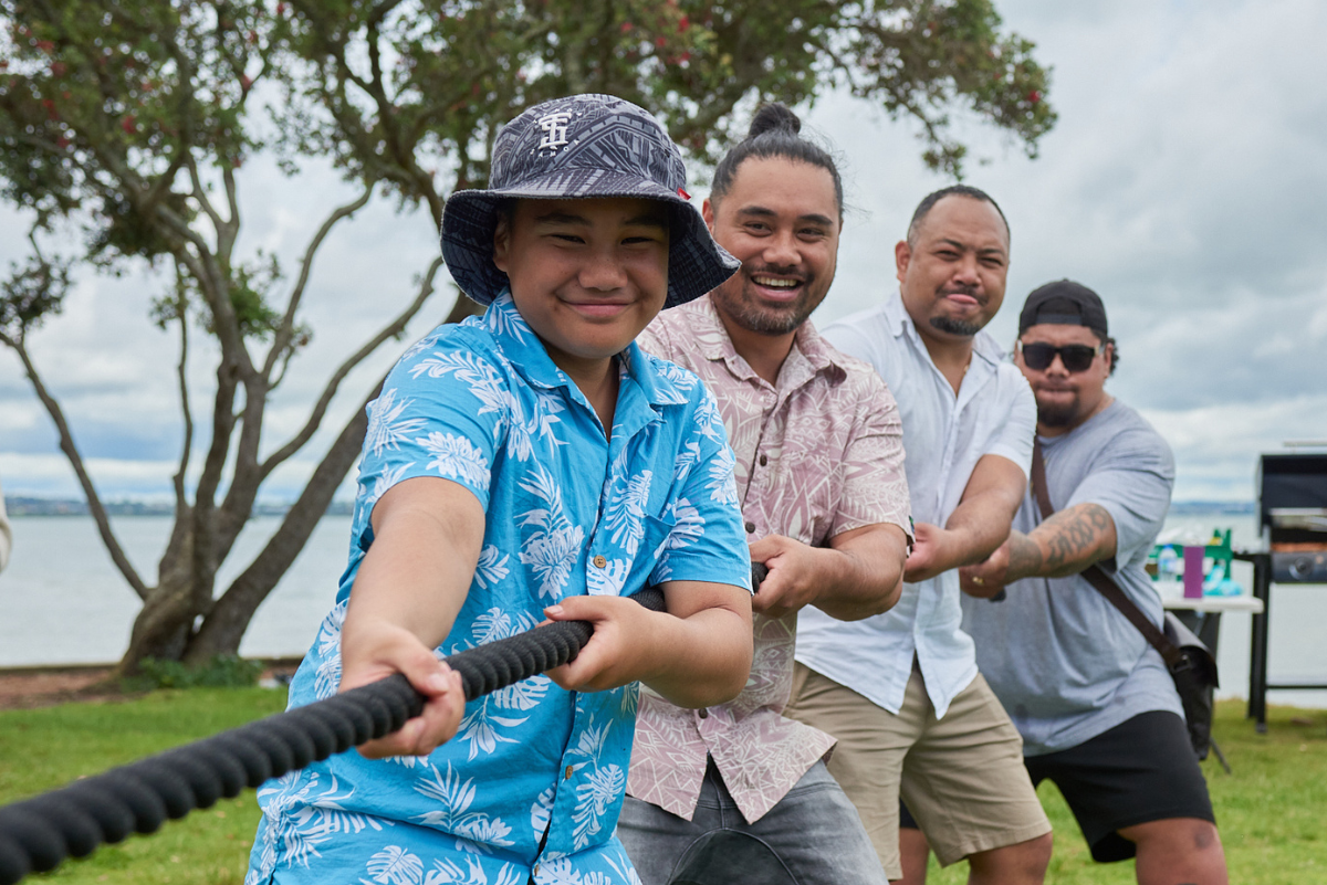 Pacific men and boy playing tug of war